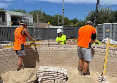 Tradesmen carefully installing bricks on a residential wall