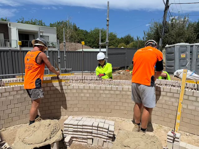 Brick Wall Installation Tradesmen carefully installing bricks on a residential wall